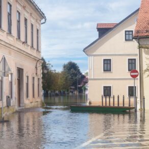 Översvämmad stadsgata med historiska hus och båt vid vattendränkt kvarter