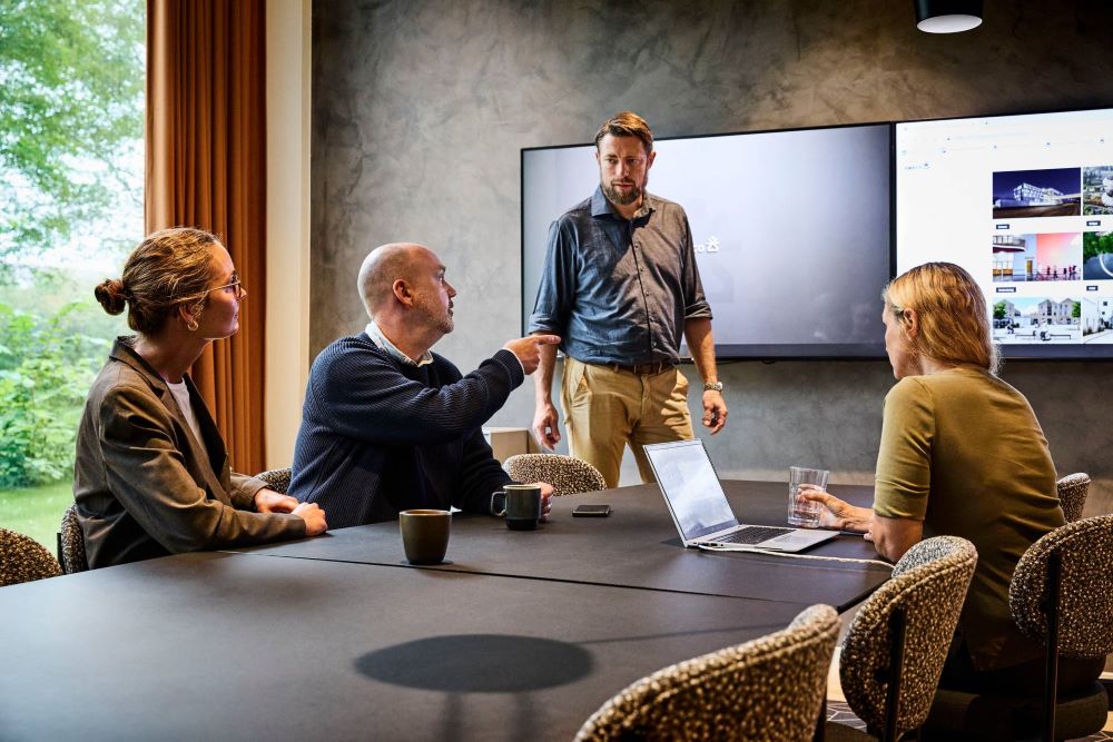 Fyra personer i ett mötesrum som diskuterar med varandra.