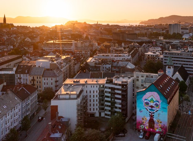 Stadsdel med lägenhetshus sett ovanifrån, i en stad med nära till vatten som syns längre bort.