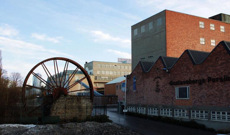 Område med byggnader i framförallt tegel samt ett stort kvarnhjul.