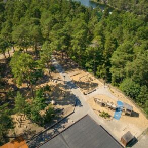 Flygfoto över skogsområde med Viktor Rydbergs skola i Nacka kommun, med en vik som skymtas i bakgrunden.