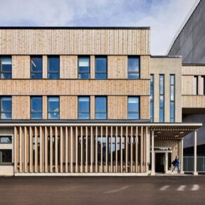 Modern byggnad med träfasad, stora fönster och entréparti i dagsljus.