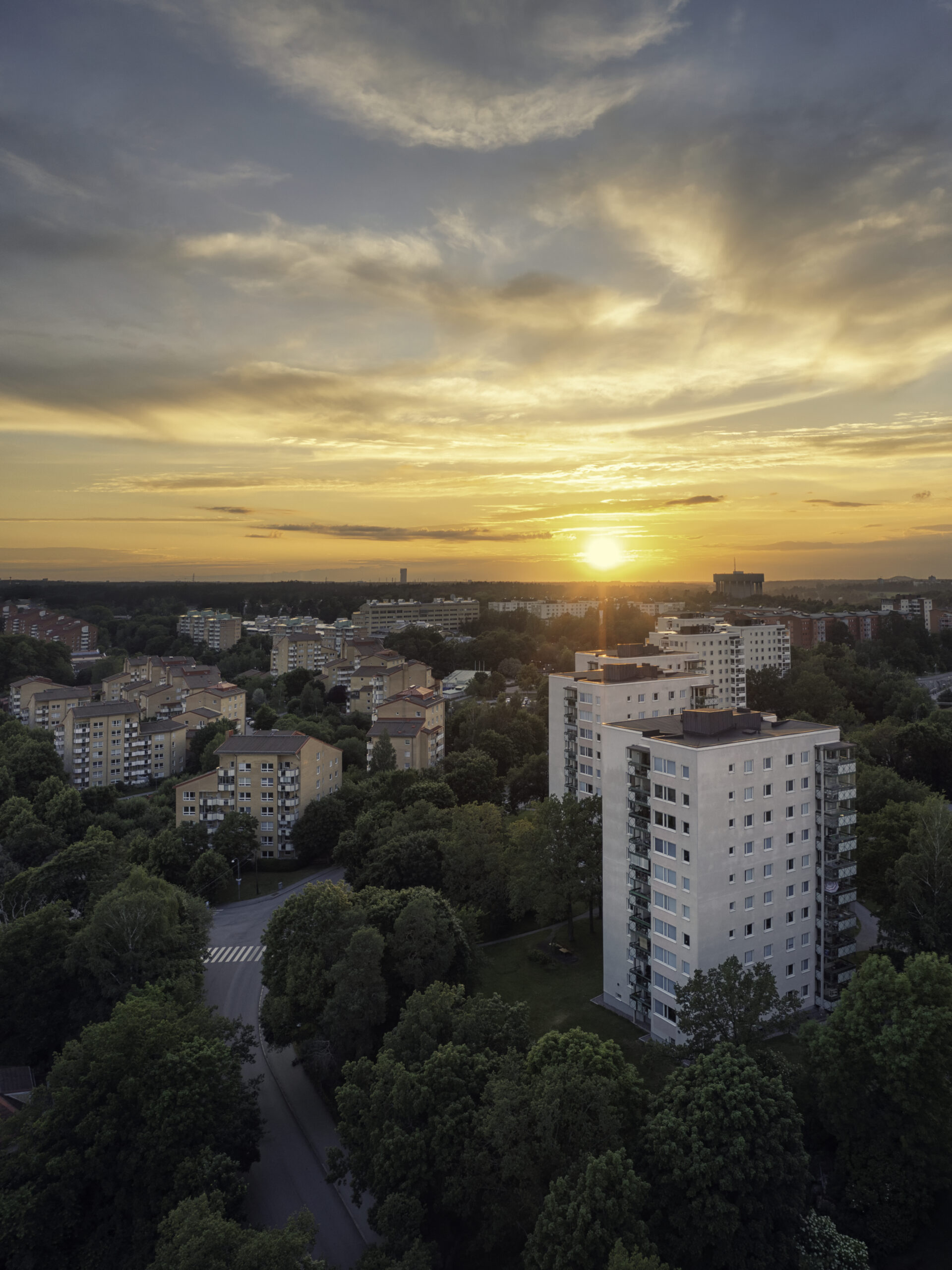 Flygfoto över flerfamiljshus i Bergshamra, Solna kommun, vid solnedgång.